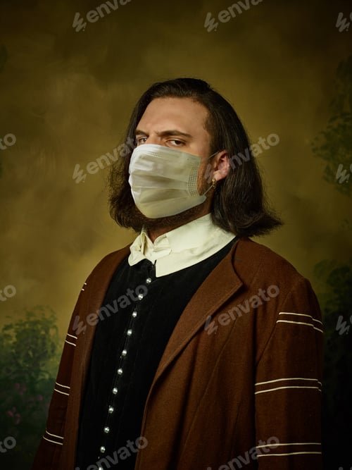 Preview: Young man as a medieval knight on dark background wearing protective mask against coronavirus