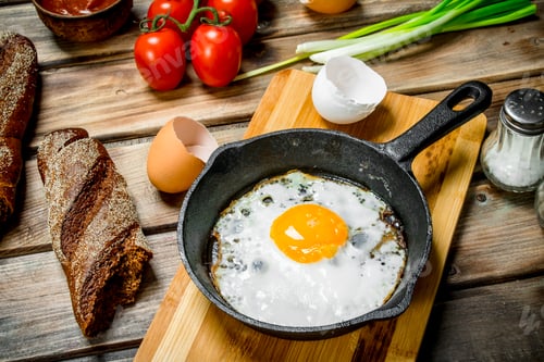 Preview: Fried egg in a pan with bread, tomatoes and green onions.