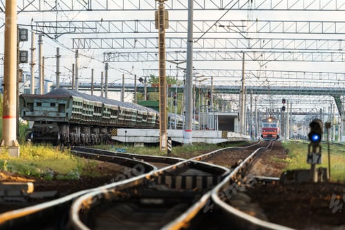 Preview: Train station platform with railway tracks at sunset and commute electric train on background.