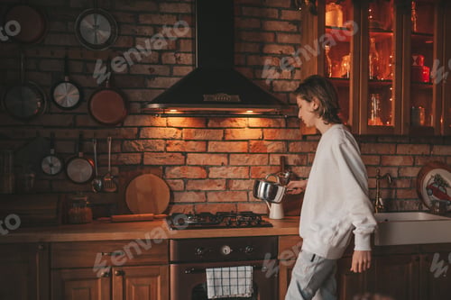 Preview: Portrait of candid authentic boy teenager holiday cooking in kitchen at wooden lodge Xmas decorated