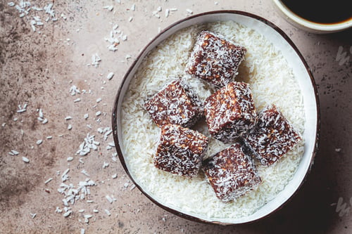 Preview: Vegan coconut and dates energy squares in coconut bowl.