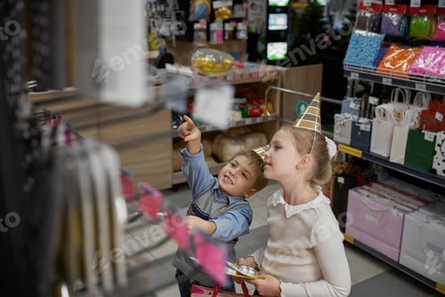 Preview: Little boy and girl kids choosing candles for birthday party at supermarket