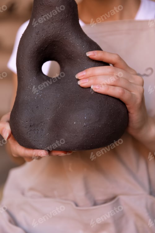 Preview: A girl with hand made vase made with clay in pottery master class room, crafted objects