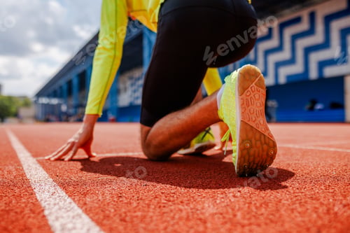 Preview: Sprinter at the starting line, ready to race on an outdoor track, wearing bright sportswear