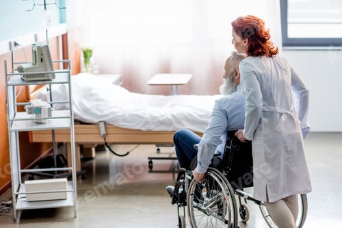 Preview: Female doctor pushing senior patient in wheelchair at hospital room