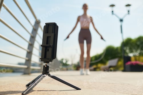 Preview: Young Woman Exercising Outdoors Using Jump Rope and Smartphone