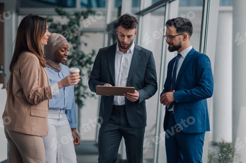 Preview: Business people discussing work using tablet in office hallway