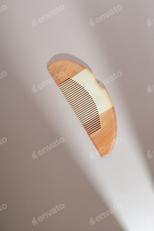 Preview: Wooden hair comb on a pastel beigr background with gobo shadow. Trendy catalogue shot