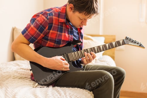 Preview: Millennial man playing, practicing electric guitar at home