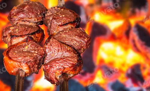 Preview: Barbecue steak on skewers roasting over a hot fire. Selective focus.