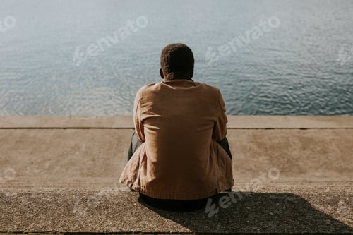 Preview: Black man sitting by the water