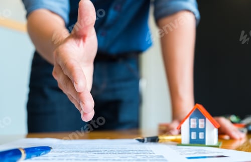 Preview: Home salesman stretches to shakes hands,Pen and model house on house plan.