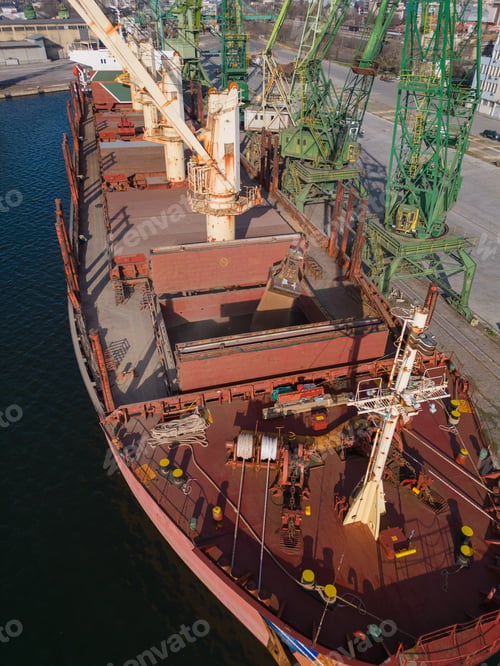 Preview: A bulk carrier ship loaded with grain is docked at a busy port, with workers and machinery seen in