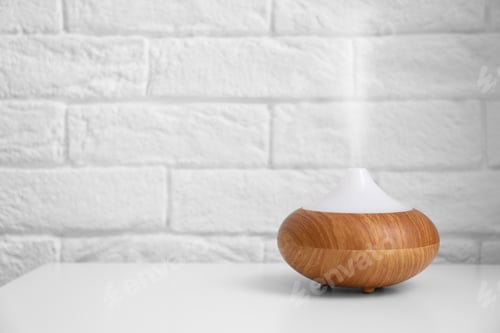 Preview: Essential oils diffuser on white table near brick wall. Space for text