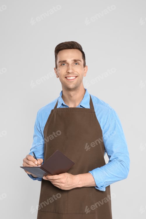 Preview: Handsome waiter in apron taking order on light background