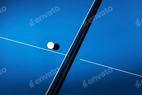 Preview: Table Tennis Ball Resting on Blue Table with Net Casting Diagonal Shadow
