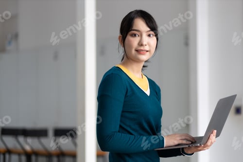 Preview: Happy young asian woman using laptop to browse internet.