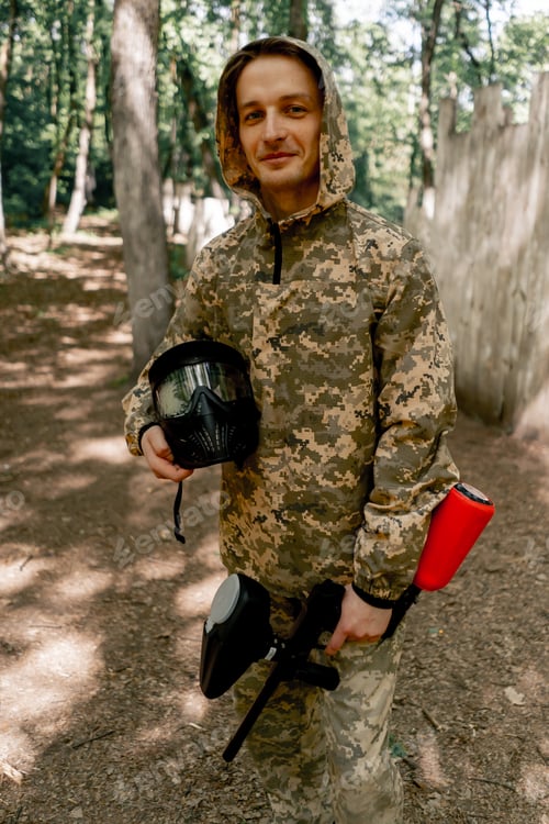 Preview: in the forest player for playing pintball a young guy ready for competition stands with a mask in