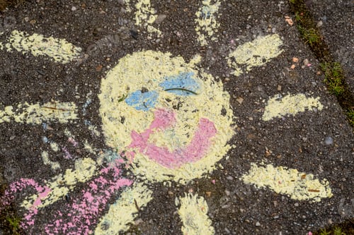 Preview: Faded chalk drawing of a sun on pavement.