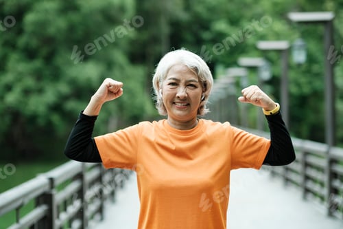 Preview: Athletic Senior woman stretching arms in park.