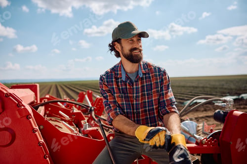 Preview: Happy farm worker using agricultural machinery while working in the field.