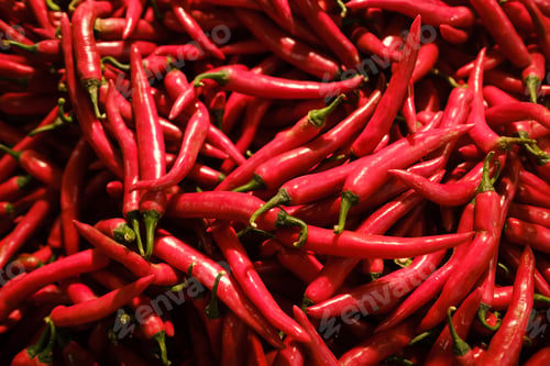 Preview: Bright red chili peppers stacked in a market setting during early morning hours, showcasing fresh