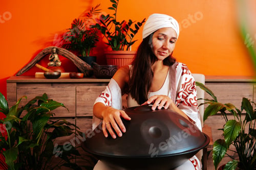 Preview: Beautiful young woman in white turban playing handpan musical instrument. Sound healing concept.