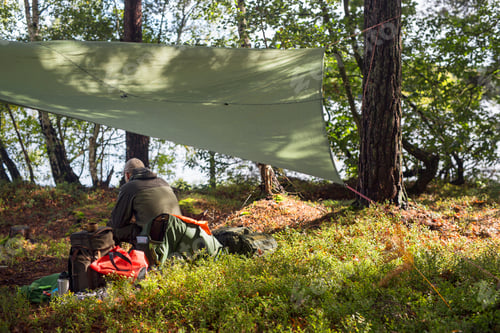 Preview: Male hiker sitting under sunshade