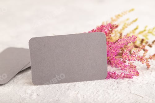 Preview: Gray paper business card mockup with purple astilbe flowers on gray concrete background