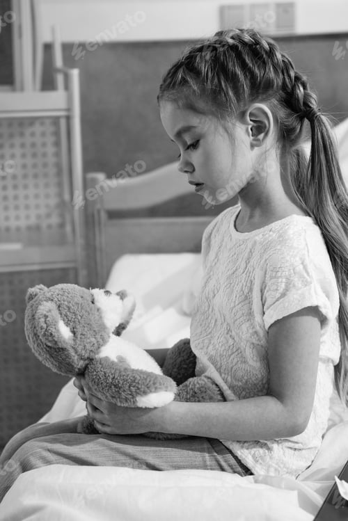 Preview: black and white portrait of upset girl looking at teddy bear in hospital
