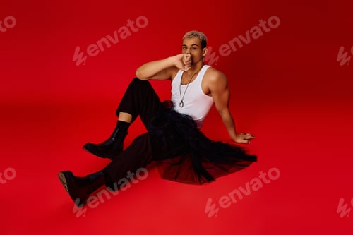 Preview: Stylish young man expresses confidence in vibrant red studio setting