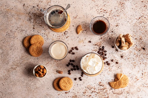 Preview: Assorted coffee drinks with ice, espresso cups and cookies on beige stone table