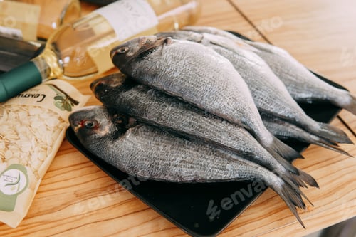 Preview: Raw Dorado fish on a black plate. Cooking Dorado in a cooking class. Raw fish, close-up.