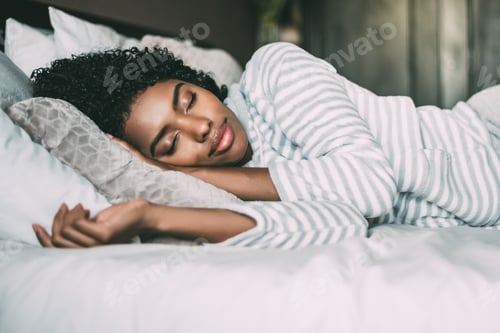 Preview: close up of a pretty black woman with curly hair sleeping in bed closed eyes