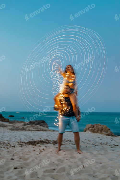 Preview: Couple playing with lights at the beach