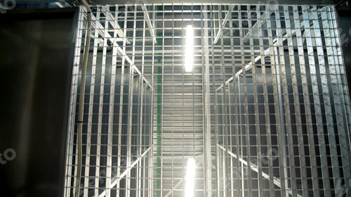 Preview: Motion under large empty metal shelves in spacious modern warehouse. Creative. Bright lamps and