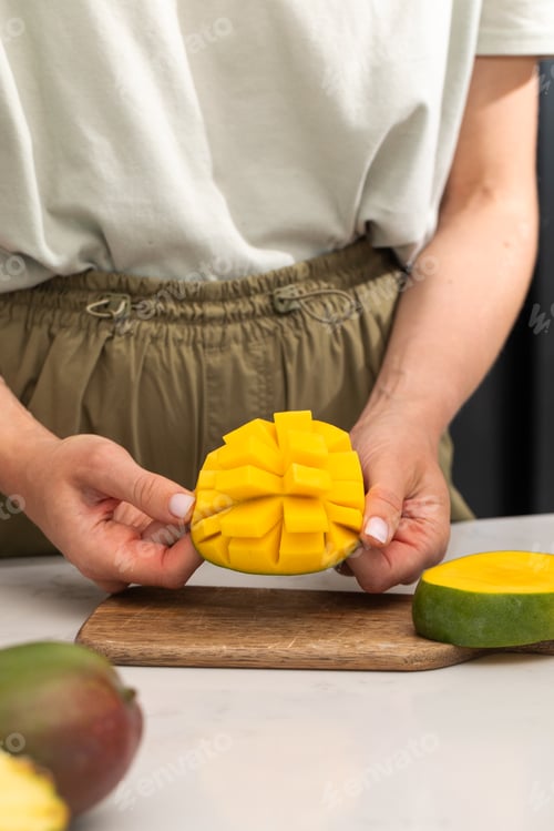 Preview: Woman holding ripe and juicy cut mango in her hands. Tropical fruits