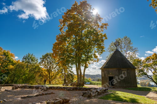 Preview: Historic wooden church with conical roof surrounded by golden autumn trees in Kernave, Lithuania