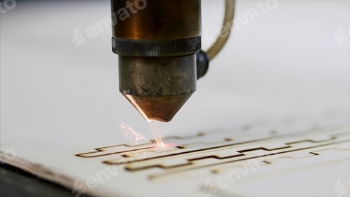 Preview: Industrial laser is cutting a pattern on a plywood sheet and moving slowly, close up.