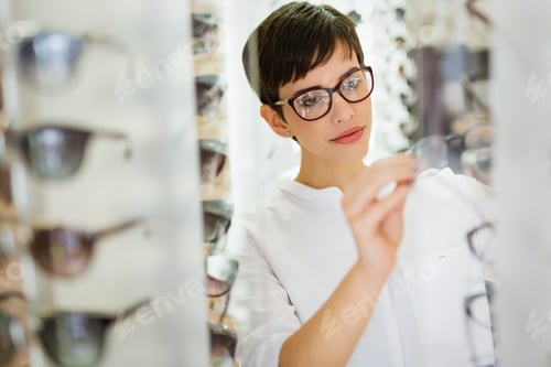 Preview: Pretty young woman is choosing new glasses at optics store