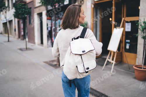 Preview: Unrecognizable trendy woman with backpack strolling on street