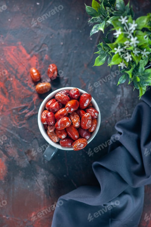 Preview: Above view of fresh raw silverberry fruits inside and outside of a gray cup and flower pot dark
