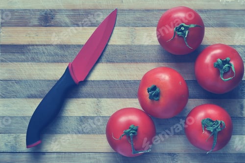 Preview: Red tomatoes and a knife on a cutting board. Toned