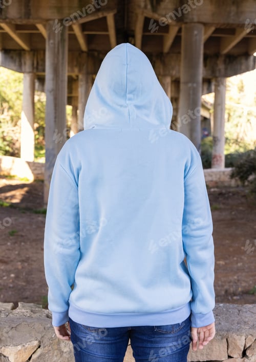 Preview: Blue haired Teenage girl in light blue oversize hoodie stand with her back to camera under bridge