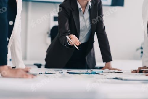 Preview: Businesswoman handing pen to colleague during meeting over financial documents