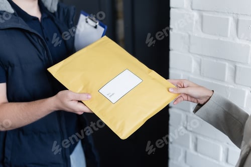 Preview: Cropped view of businesswoman taking parcel from courier with clipboard in office