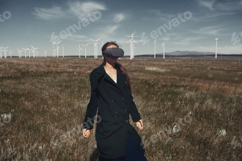 Preview: Woman with VR headset standing next to wind turbines
