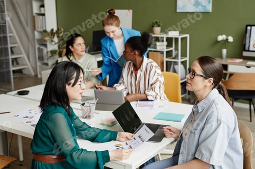 Preview: Business colleagues discussing report at meeting