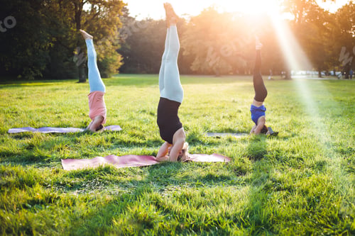 Preview: Yoga at park, group of mixed age women doing salamba sirsasana pose headstand exercise