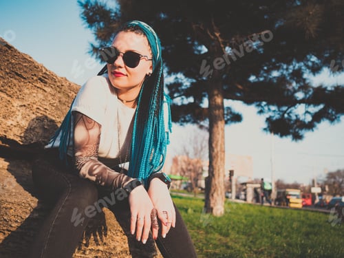 Preview: Stylish young beautiful woman with blue box african braids on the street